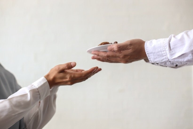 Close up of one person handing a gift to another